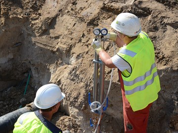 Zwei Mitarbeiter arbeiten in einer Baugrube an Leitungen Zwei Mitarbeiter arbeiten in einer Baugrube an Leitungen