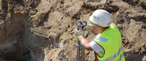 Zwei Mitarbeiter arbeiten in einer Baugrube an Leitungen Zwei Mitarbeiter arbeiten in einer Baugrube an Leitungen