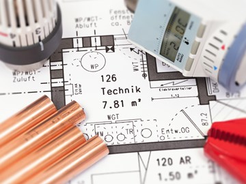 Nahaufnahme einer Bauzeichnung, auf dem Plan liegen Heizungsteile Nahaufnahme einer Bauzeichnung, auf dem Plan liegen Heizungsteile