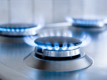 Drei blaue Gasflammen auf einem silbernen Gasherd - Nahaufnahme Drei blaue Gasflammen auf einem silbernen Gasherd - Nahaufnahme