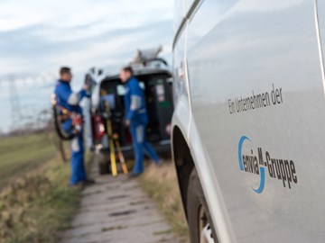 Mitarbeiter an einem Technikfahrzeug auf einem Feldweg Mitarbeiter an einem Technikfahrzeug auf einem Feldweg