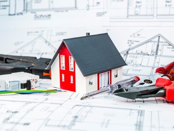 Kleines Hausmodell und Werkzeug auf einem Bauplan Kleines Hausmodell und Werkzeug auf einem Bauplan