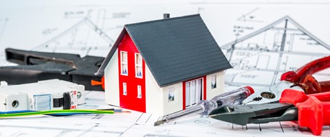 Kleines Hausmodell und Werkzeug auf einem Bauplan Kleines Hausmodell und Werkzeug auf einem Bauplan