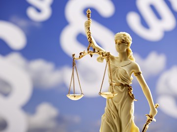 Justitia-Statue vor einem blauen Hintergrund mit weißen Paragrafenzeichen - Bildmontage Justitia-Statue vor einem blauen Hintergrund mit weißen Paragrafenzeichen - Bildmontage