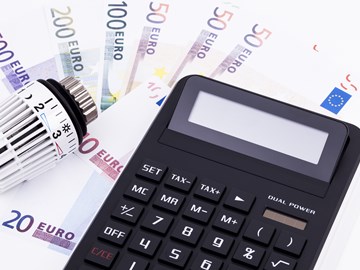 Geldscheine, ein Taschenrechner und ein Temperaturregler einer Heizung - Nahaufnahme Geldscheine, ein Taschenrechner und ein Temperaturregler einer Heizung - Nahaufnahme