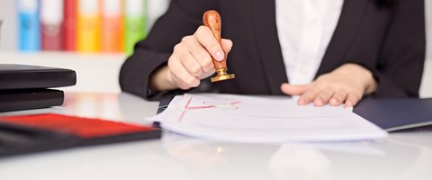 Hände einer Frau mit Siegelstempel über einer Urkunde Hände einer Frau mit Siegelstempel über einer Urkunde